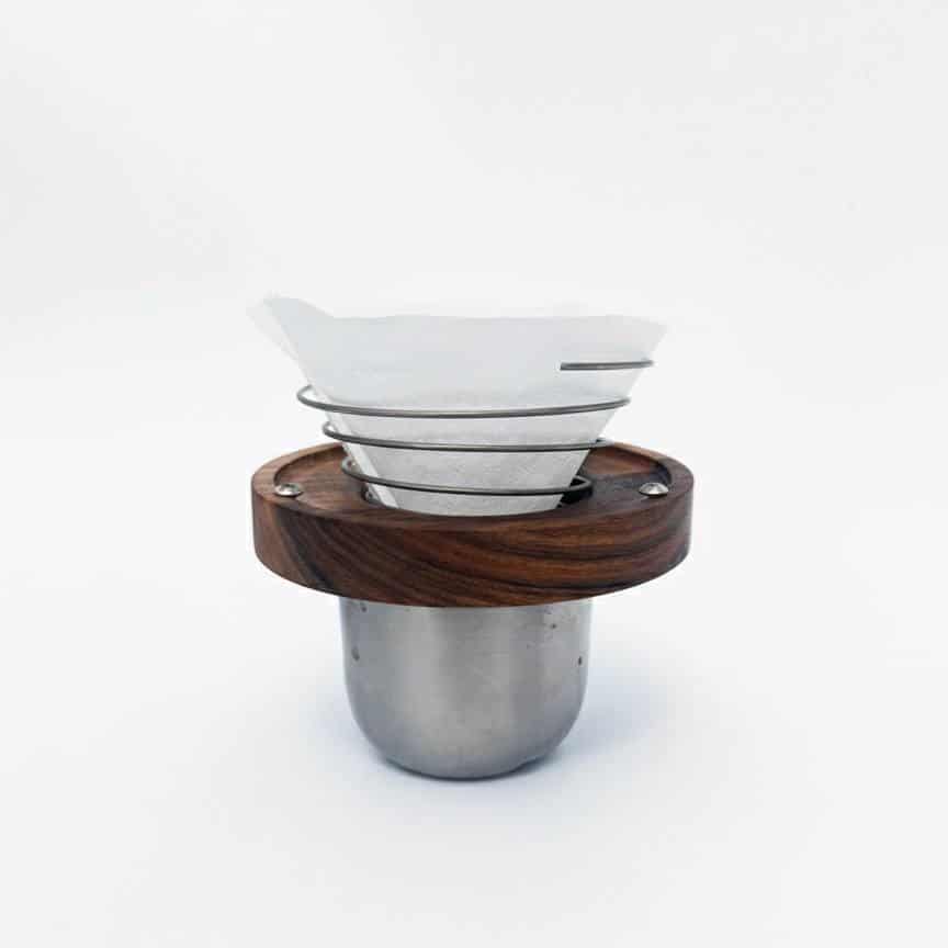 دم افزار اسپرو (Sprew) دم افزار اسپرو با فریم چوبی تیره روی یک فنجان استیل بهمراه فیلتر و آماده برای دم آوری.