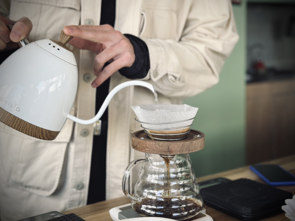 بررسی دم آوری قهوه به روش ۱۱-۱۱ و مقایسه دو دم افزار اسپرو و v60-01 سرامیکی در این شیوه باریستا در حال ریختن آب درون دم افزار اسپرو